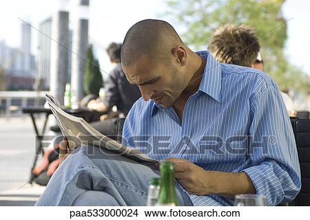 Picture - Man sitting at sidewalk cafe, reading newspaper. Fotosearch