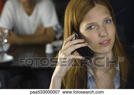 Woman holding cell phone to ear, smiling at camera View Large Photo Image Stock Photo - Woman holding cell phone to ear, smiling at camera. Fotosearch