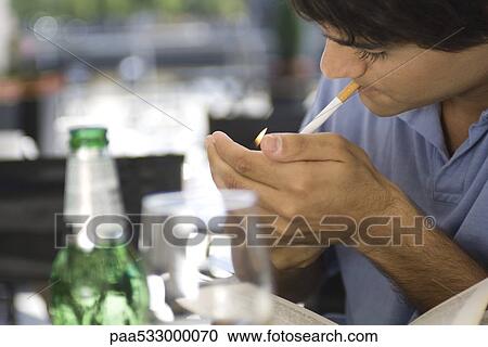 Stock Image - Young man lighting cigarette. Fotosearch