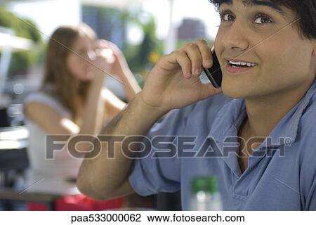 Stock Image - Young man talking on cell phone, close-up. Fotosearch