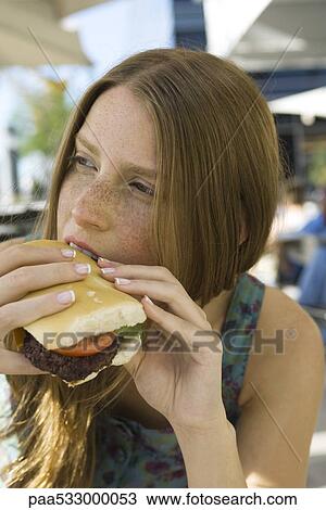 Young woman biting into hamburger View Large Photo Image Stock Image - Young woman biting into hamburger. Fotosearch