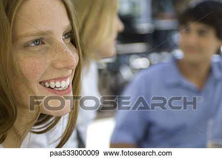 Young woman smiling, friends in background View Large Photo Image Stock Photo - Young woman smiling, friends in background. Fotosearch