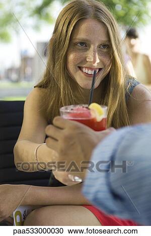 Young woman taking cocktail from friend View Large Photo Image Stock Image - Young woman taking cocktail from friend. Fotosearch