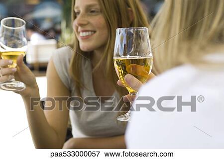 Stock Photo - Young women drinking beer at sidewalk cafe, cropped. Fotosearch