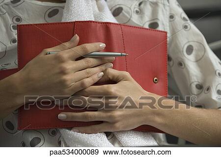 Stock Photo - Woman holding diary on chest, cropped view. Fotosearch