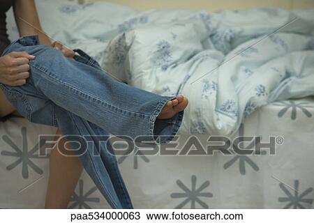 Stock Image - Woman putting on jeans, cropped view. Fotosearch