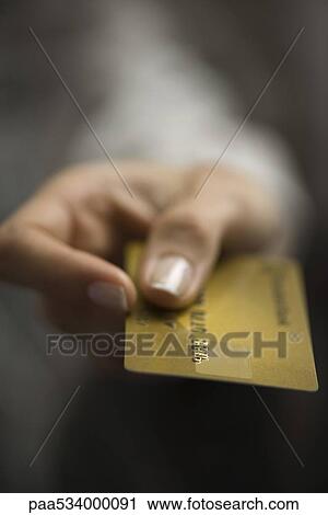 Stock Image - Woman's hand holding out credit card, extreme close-up. Fotosearch