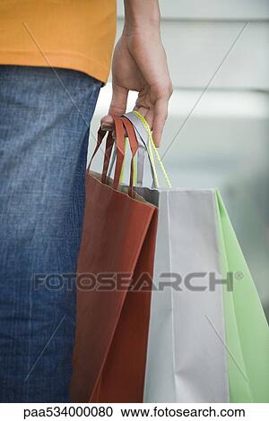 Stock Image - Woman's hand holding shopping bags, close-up. Fotosearch