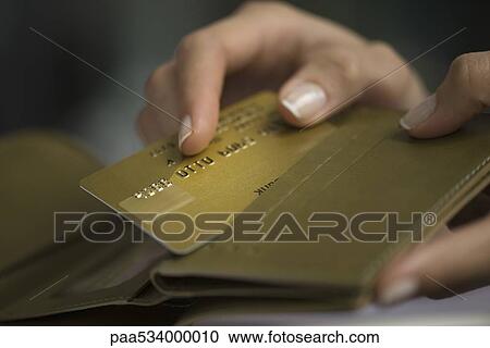 Stock Image - Woman's hand taking credit card out of wallet. Fotosearch