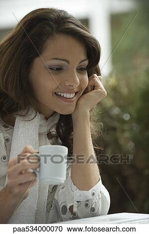 Young woman drinking coffee and looking at laptop computer View Large Photo Image Stock Image - Young woman drinking coffee and looking at laptop computer. Fotosearch