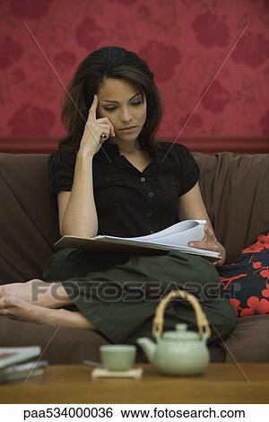 Young woman reading document on sofa View Large Photo Image Stock Photograph - Young woman reading document on sofa. Fotosearch