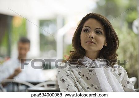 Stock Photo - Young woman sitting in sidewalk cafe, smiling. Fotosearch