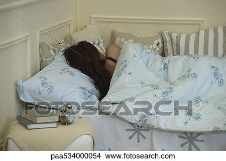 Picture - Young woman sleeping in bed, rear view. Fotosearch