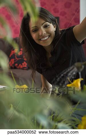 Young woman smiling at flowering house plant View Large Photo Image Stock Image - Young woman smiling at flowering house plant. Fotosearch