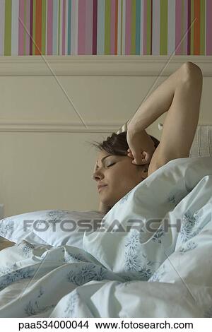 Picture - Young woman waking up in bed. Fotosearch