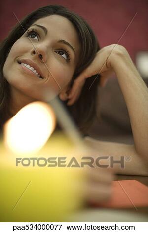 Young woman writing, holding head and looking up, candle in foreground View Large Photo Image Stock Photo - Young woman writing, holding head and looking up, candle in foreground. Fotosearch