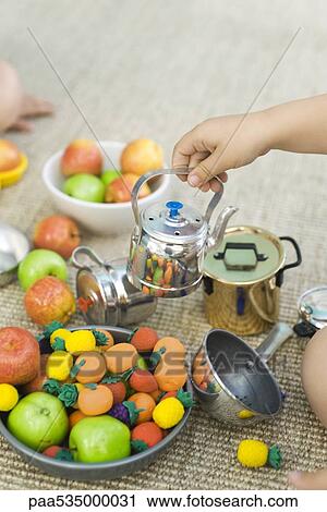 Stock Image - Children playing with teapot and fake food, cropped view. Fotosearch