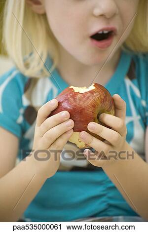 Stock Image - Little girl eating apple, cropped. Fotosearch