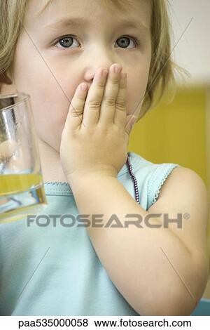 Little girl holding glass of juice, covering mouth with one hand View Large Photo Image Stock Photo - Little girl holding glass of juice, covering mouth with one hand. Fotosearch