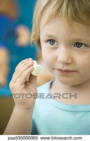 Stock Photography - Little girl holding marshmallow, close-up. Fotosearch