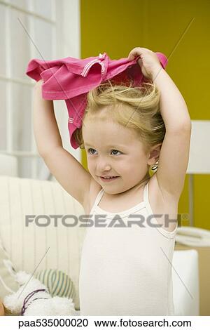 Stock Image - Little girl holding shirt over her head. Fotosearch