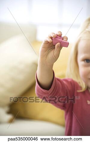 Stock Photograph - Little girl holding up handful of pink clay, cropped. Fotosearch