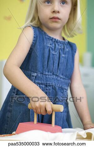 Stock Image - Little girl ironing with toy iron. Fotosearch
