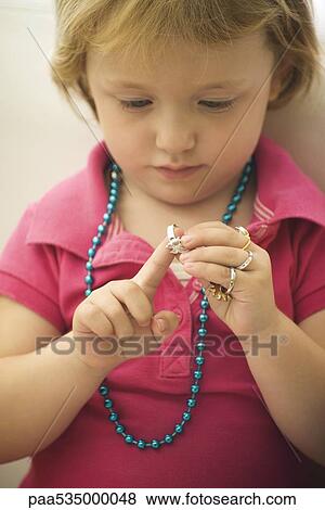 Stock Photo - Little girl playing with costume jewelry, putting on ring. Fotosearch