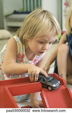 Stock Image - Little girl playing with toy car. Fotosearch