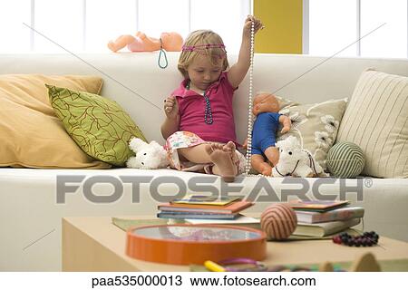 Little girl playing with toys and costume jewelry on sofa View Large Photo Image Stock Image - Little girl playing with toys and costume jewelry on sofa. Fotosearch