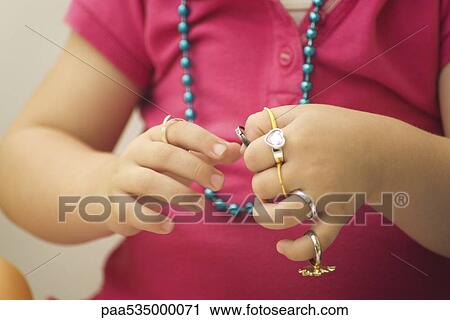 Stock Image - Little girl putting on plastic rings, cropped view. Fotosearch