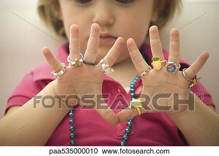 Little girl wearing several plastic rings on fingers, close-up View Large Photo Image Stock Image - Little girl wearing several plastic rings on fingers, close-up. Fotosearch
