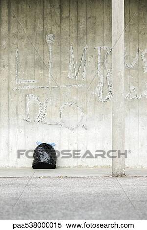 Stock Photography - Bag of garbage leaning against wall. Fotosearch