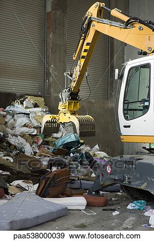 Earth mover picking up trash from large heap View Large Photo Image Stock Photo - Earth mover picking up trash from large heap. Fotosearch