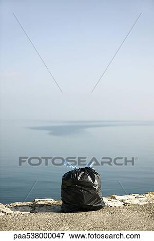 Garbage bag on ledge with sea in background View Large Photo Image Stock Photo - Garbage bag on ledge with sea in background. Fotosearch