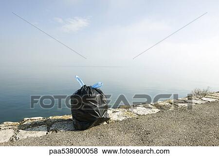 Garbage bag on ledge with sea in background View Large Photo Image Stock Photo - Garbage bag on ledge with sea in background. Fotosearch