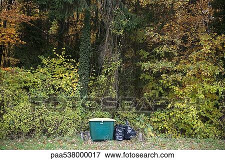 Stock Photo - Garbage bags and compost bin in wooded landscape. Fotosearch