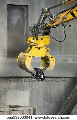 Stock Image - Grapple picking up single garbage bag. Fotosearch