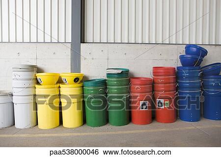 Stock Photograph - Multicolored garbage cans and recycling bins stacked along wall. Fotosearch