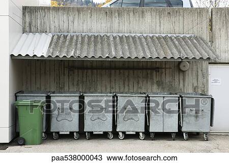 Stock Image - Trash bins lined up under awning. Fotosearch