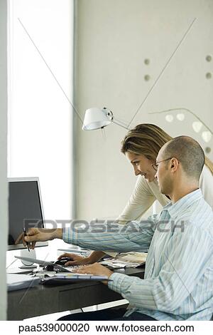 Stock Image - Couple in home office, looking at computer together. Fotosearch