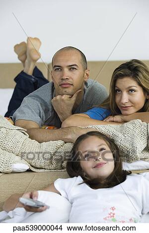 Picture - Family relaxing, watching TV together. Fotosearch