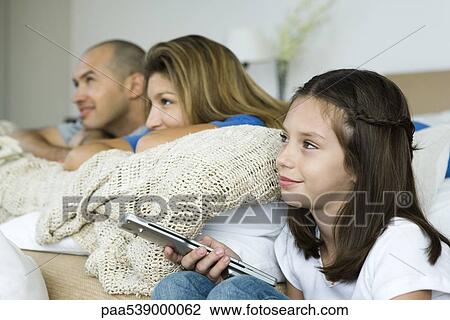 Family watching TV together, girl holding remote control View Large Photo Image Stock Image - Family watching TV together, girl holding remote control. Fotosearch