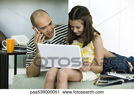 Father and daughter looking at laptop computer together, man using cell phone View Large Photo Image Stock Image - Father and daughter looking at laptop computer together, man using cell phone. Fotosearch