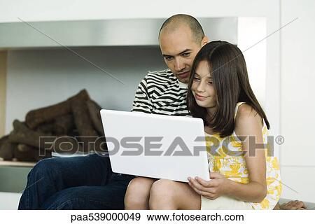 Stock Photo - Father and daughter looking at laptop computer together. Fotosearch