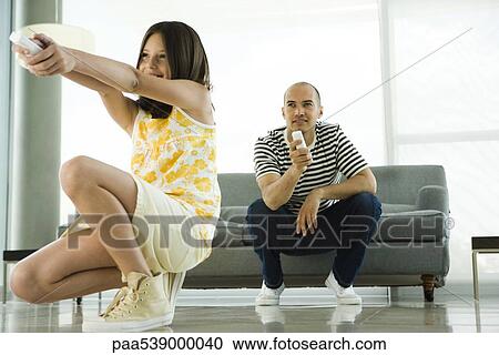 Stock Image - Father and daughter playing video game with wireless controllers. Fotosearch