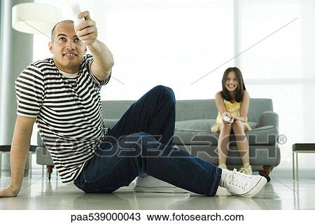 Stock Image - Father and daughter playing video game with wireless controllers. Fotosearch