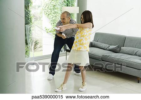 Stock Photography - Father and daughter playing video game with wireless controllers. Fotosearch