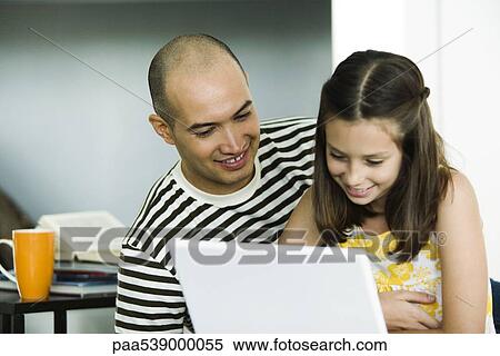 Stock Photography - Father and daughter using laptop computer together. Fotosearch