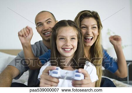 Stock Photo - Girl playing video game, parents watching and cheering. Fotosearch